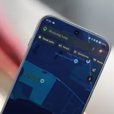 Na ekranie telefonu widać mapy googlr z zaznaczonym stadionem i opcjami wyszukiwania: stacje paliw, hotele, spożywcze, restauracje.